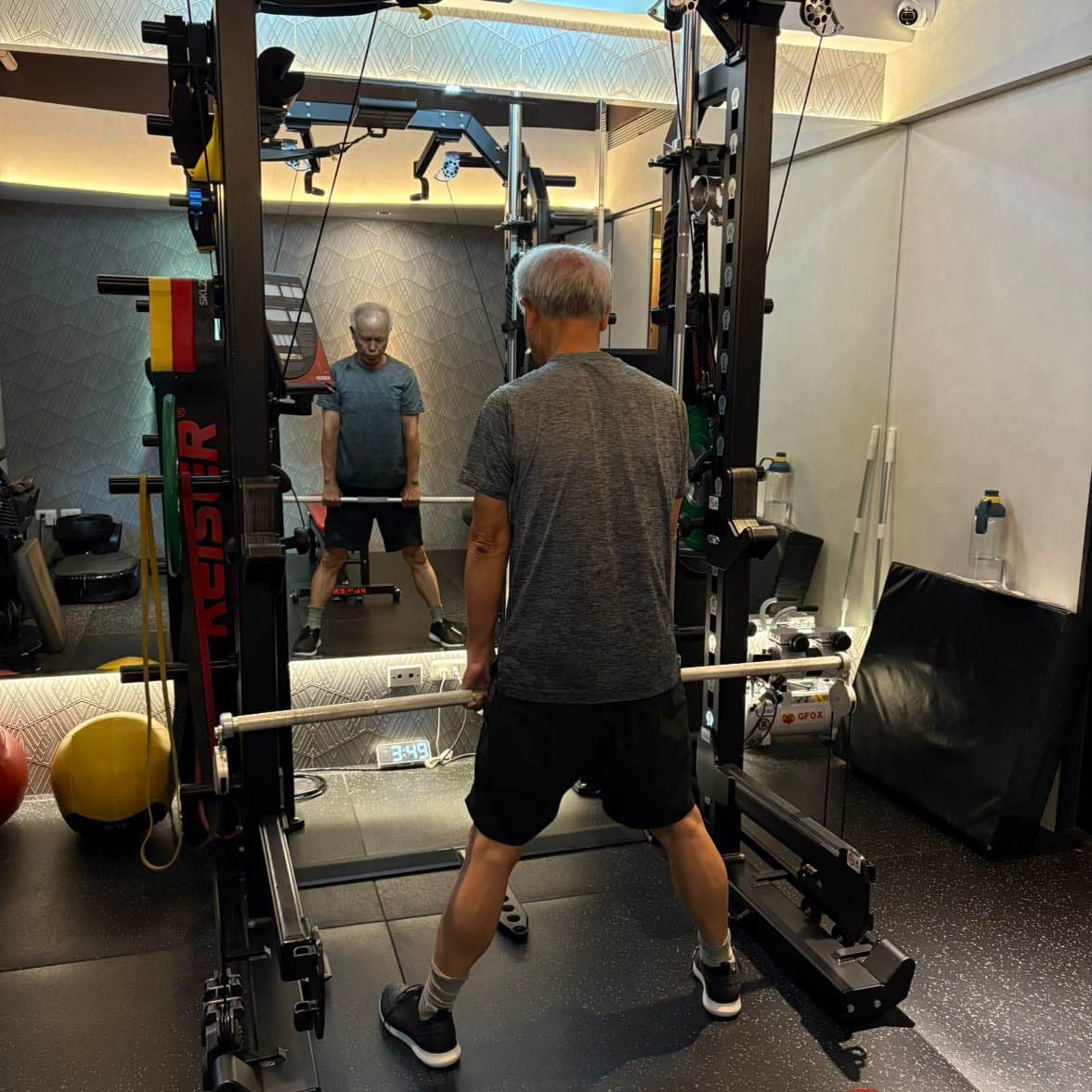 張立秋在鏡前 Keiser 訓練架內雙手持槓,鏡中可見正面。